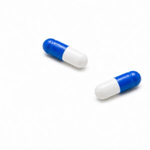 Zwei blau-weiße „Novacana THC Kapseln 2,5 mg“ mit einem Gehalt von jeweils 2,5 mg liegen auf einer schlichten weißen Fläche, im Abstand zueinander, ohne dass weitere Gegenstände im Bild zu sehen sind.